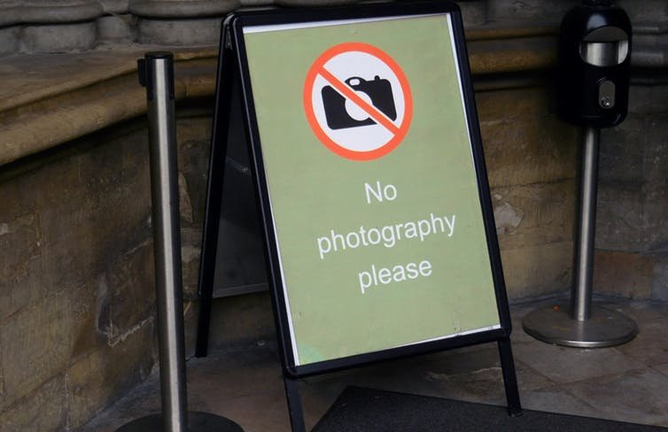 Why is taking photographs banned in many museums and historic places?